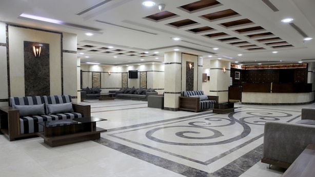 A spacious lobby with a reception desk, sofas, and a patterned floor.
