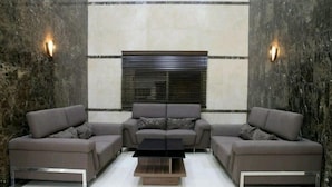 A modern living room with a sectional sofa, a coffee table, and a window with blinds.