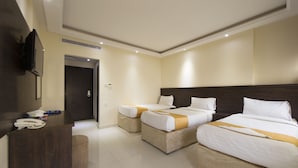 A hotel room with two beds, a desk, and a TV.