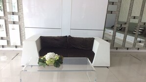 Ein modernes Wohnzimmer mit einem weißen Sofa, einem Glastisch und einer Zimmerpflanze.