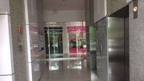 Ein modernes Interieur mit Glastür, sichtbarem Aufzug und Hinweisschild für Parkplatz und Food Court.