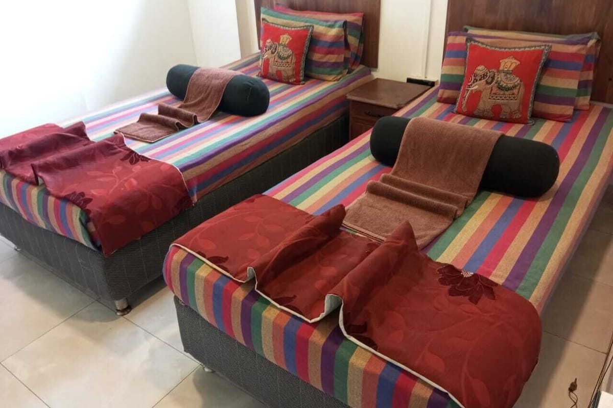 A hotel room with two single beds, each with a striped bedspread and matching pillows.