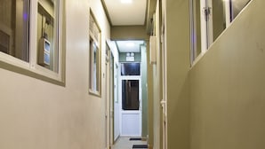 A narrow hallway with a wooden floor, beige walls, and windows on both sides. - Kandy City Rooms & Hostel (Kandy)