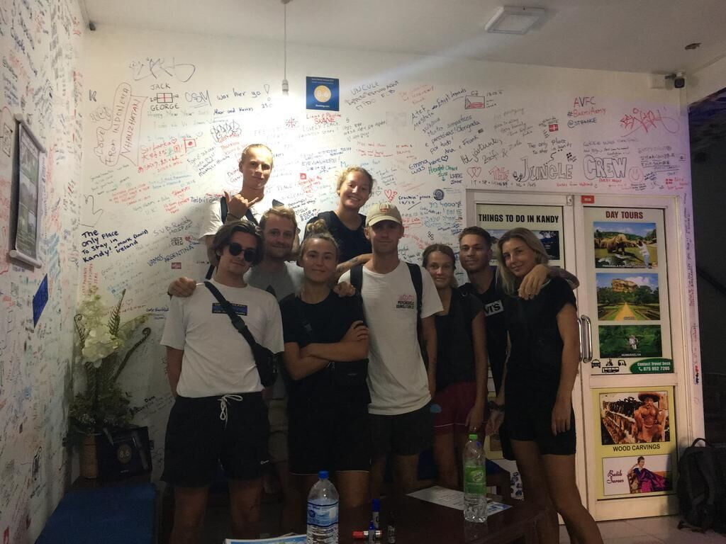 Eine Gruppe von Personen in einem Raum mit einer Tafel voller Notizen und einer Tür mit einem Plakat.