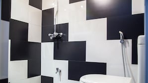 A bathroom with black and white checkered tiles, a white toilet, and a shower with a handheld showerhead. - Kandy City Rooms & Hostel (Kandy)
