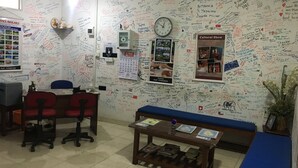 A reception area with a whiteboard covered in various writings and a clock. There is a desk with a computer, a chair, and a small table with magazines. - Kandy City Rooms & Hostel (Kandy)