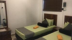 A room with two single beds, each with a striped bedspread and pillows, a wooden headboard, and a mirror on the left wall. - Kandy City Rooms & Hostel (Kandy)
