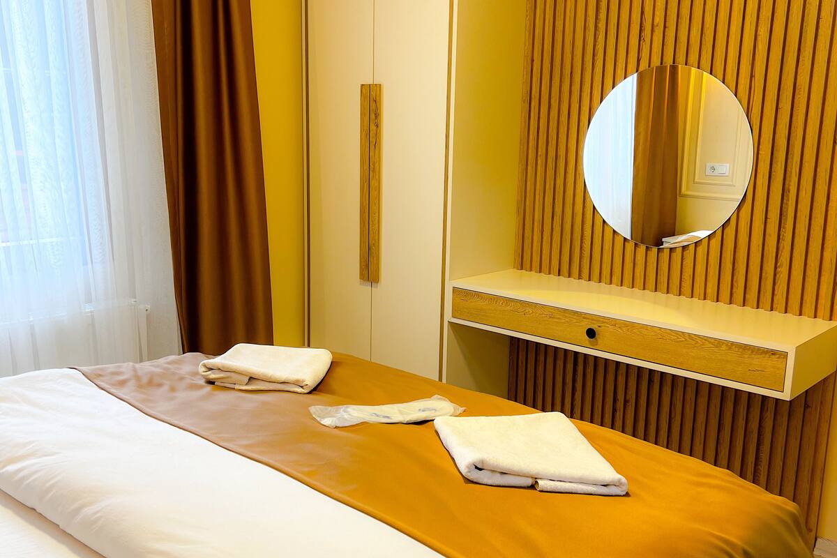 A hotel room with a bed, a bedside table, a mirror, and a wardrobe.
