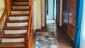 Una escalera de madera que conduce a un pasillo con una alfombra estampada y paredes de madera.
