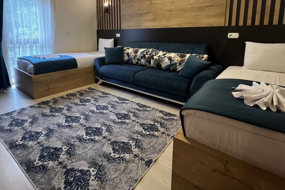 A modern bedroom with a large bed, a sofa, and a small seating area.