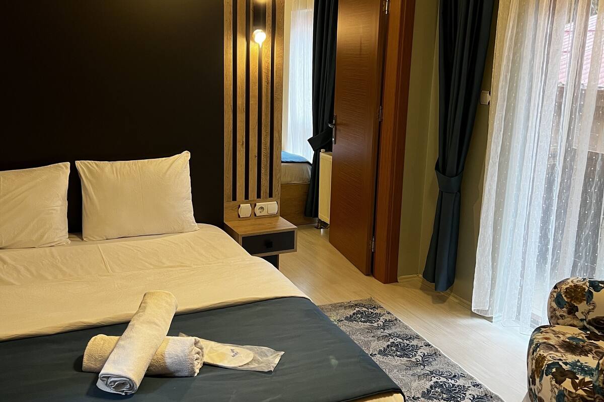 A hotel room with a large bed, a wooden nightstand, a mirror, and a floral armchair.