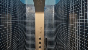 A shower enclosure with a vertical control panel and tiled walls. - Villa Agrikoia (Santorini)