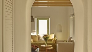A cozy room with a sofa, a small table, and a vase of flowers. - Villa Agrikoia (Santorini)