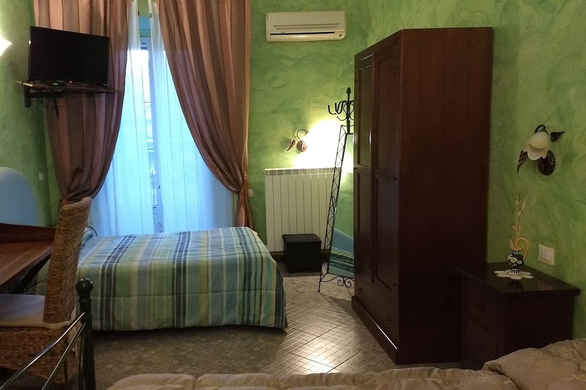 Una habitación con cama, escritorio, armario y radiador.