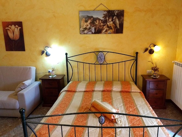 A bedroom with a bed, nightstands, a lamp, a chair, and a painting on the wall.