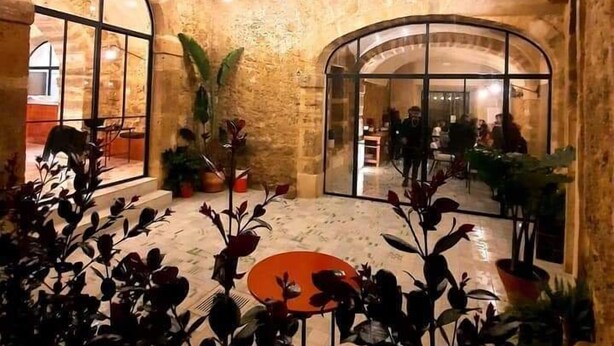Un amplio atrio con altos arcos de piedra, una zona de estar central y vistas al comedor interior.