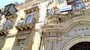 Un edificio histórico con balcones ornamentales, una amplia entrada en arco y un letrero que indica un negocio.