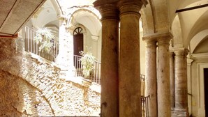 Un interior con columnas de piedra, una escalera y una barandilla.