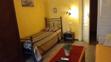 A bedroom with a bed, bedside table, lamp, and a small potted plant.