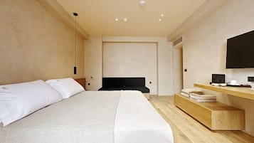 A modern hotel room with a large bed, a wooden bedside table, a flat-screen TV, and a built-in desk.