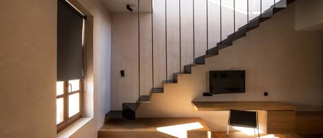 Un interior moderno con una escalera, suelo de madera y una zona de escritorio.