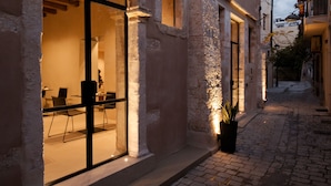 A historic building with an arched entrance, a visible seating area inside, and a cobblestone street. - Monastery Estate Venetian Harbor (Chania)
