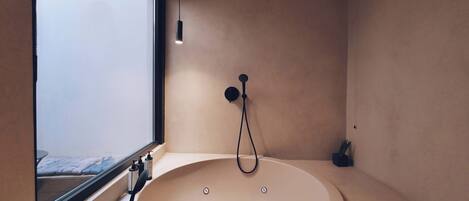 A modern bathroom with a bathtub, a window, and a shower head.