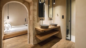 A modern bathroom with a wooden bench, two large round sinks, and a mirror above the sink. - Monastery Estate Venetian Harbor (Chania)
