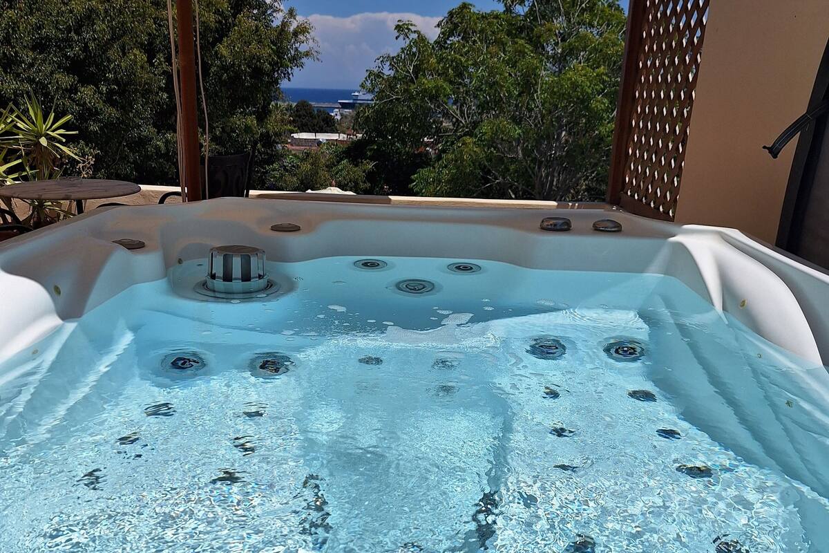 Un jacuzzi con vistas despejadas del entorno, incluyendo árboles y una vista distante del océano.