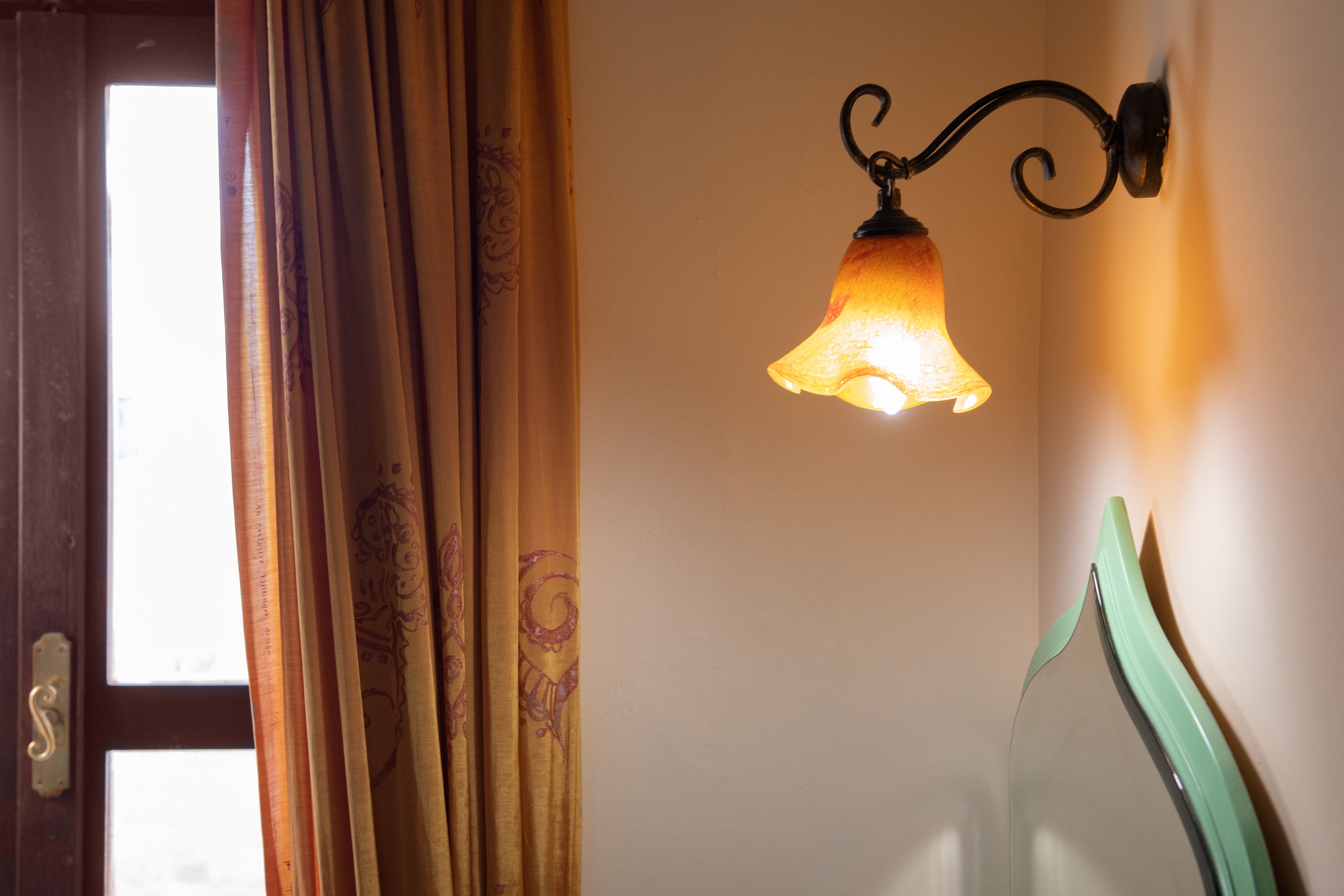 A room with a door, curtains, and a wall-mounted light fixture.