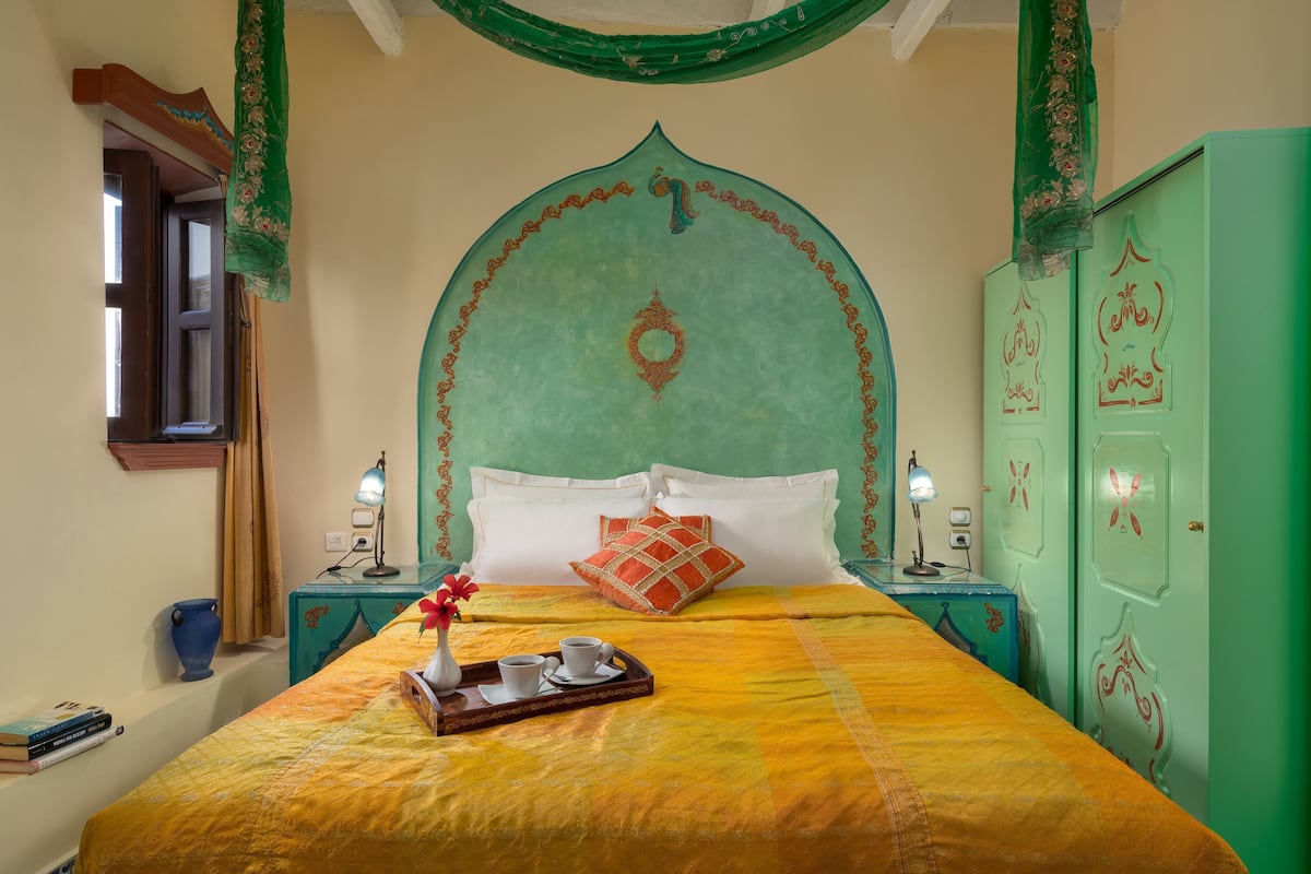 Una habitación con una cama, mesitas de noche, un armario verde y una ventana.