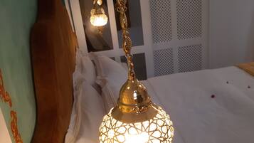 A room with a hanging lamp, a wooden headboard, and a bed with white linens.