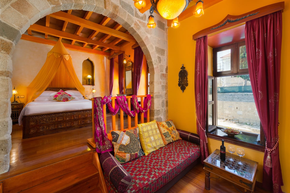 Una habitación con una cama, un sofá y un ventanal con cortinas.