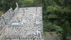 A rooftop with a zebra-striped floor pattern, surrounded by dense greenery. - Slightly Chilled Yellow House (Nallathanniya)