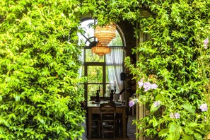 A room with a wooden table and chairs, a chandelier, and a window with curtains. - Corte della Maestà Antiche Residenze (Bagnoregio)