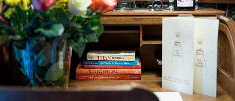 Uma escrivaninha de madeira com um vaso de flores, uma garrafa de vinho e vários livros.