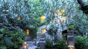 Un sentier de jardin bordé de lanternes, de murs en pierre et de verdure.