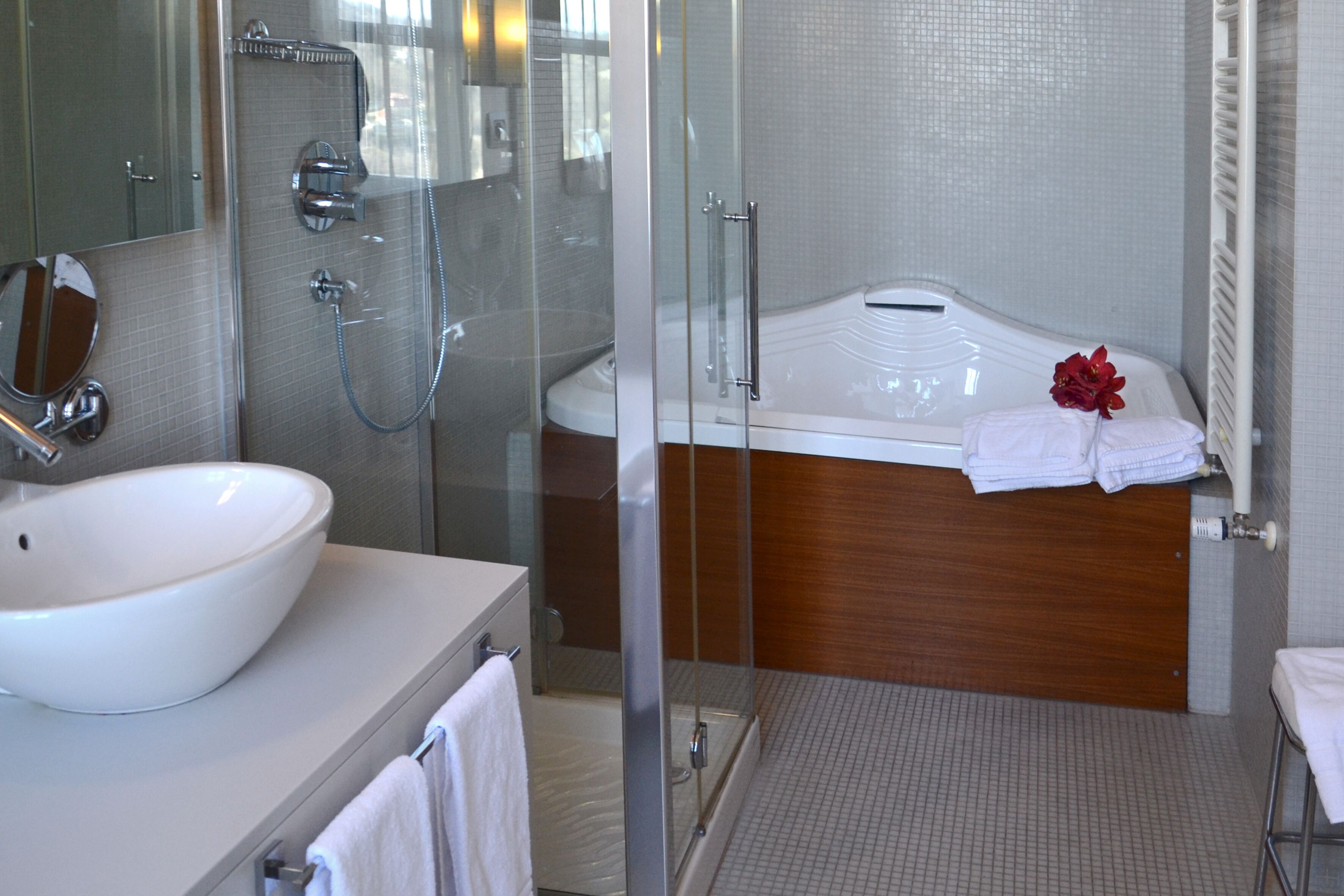 A modern bathroom with a glass-enclosed shower, a white sink, and a wooden vanity.