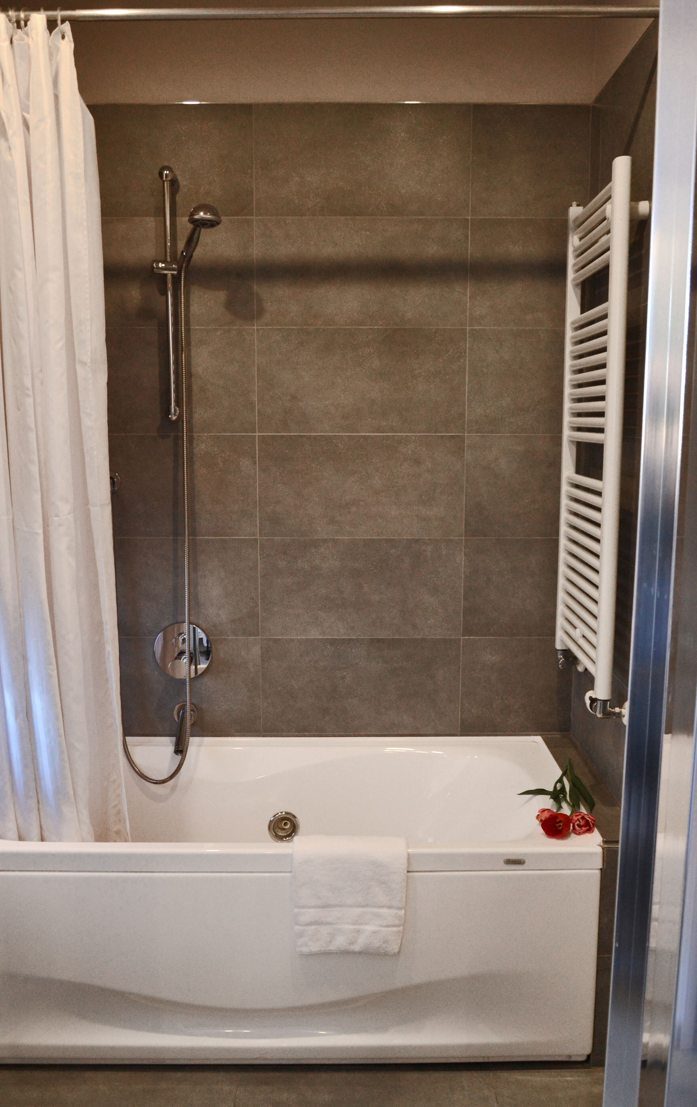 A modern bathroom with a bathtub, a shower, and a towel rack.