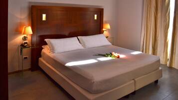 A neatly made bed with a wooden headboard, two bedside lamps, and a flower arrangement on the bed.