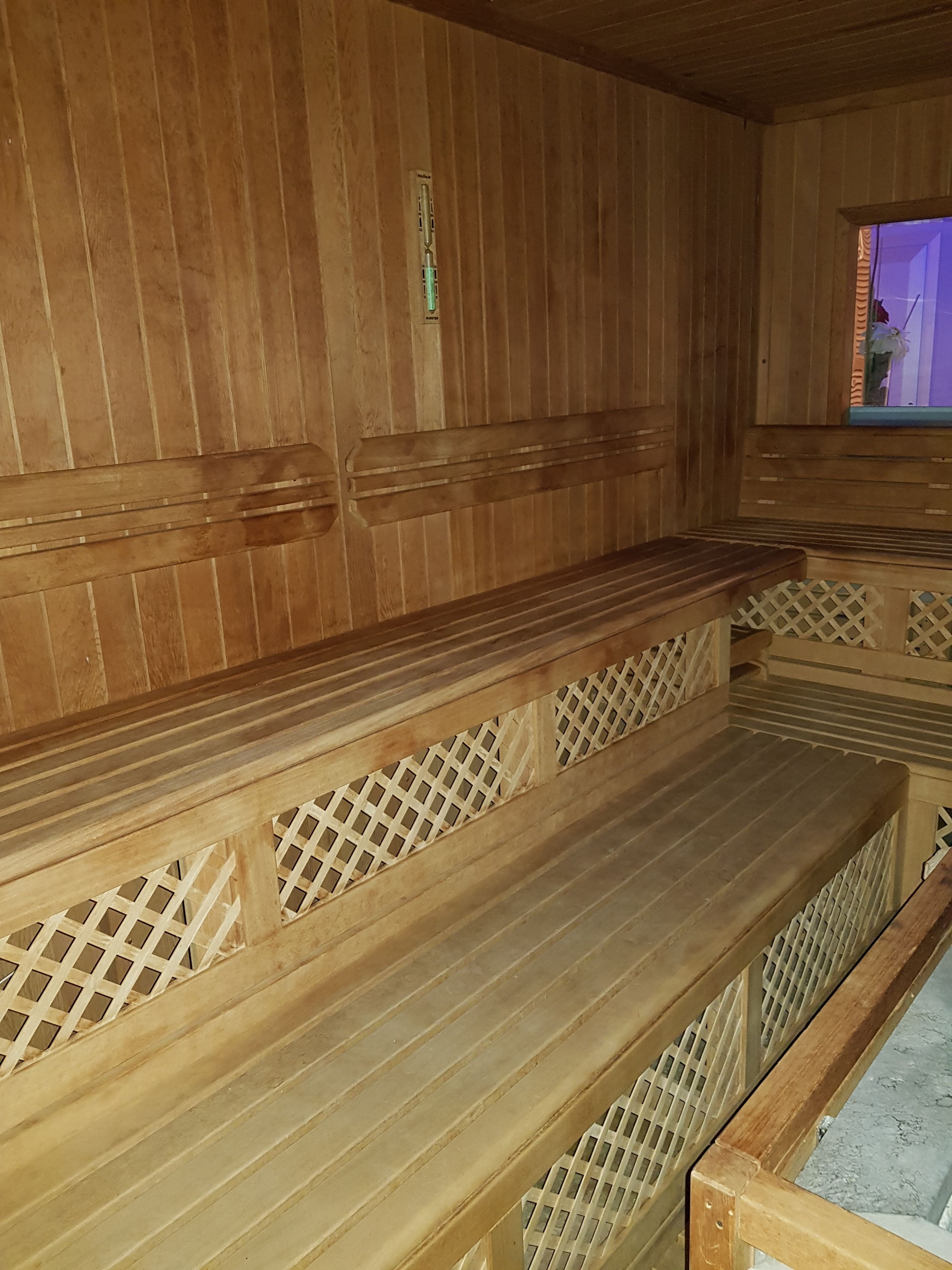 A sauna with wooden benches and lattice railings.