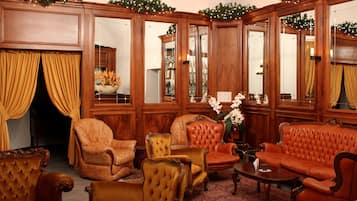 A traditional room with wooden paneled walls, a large mirror, and classic leather sofas and armchairs.