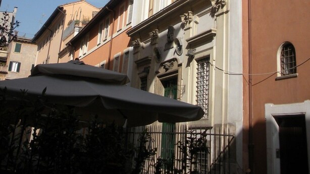 Um edifício com detalhes arquitetônicos clássicos, incluindo esculturas ornamentadas e uma varanda.