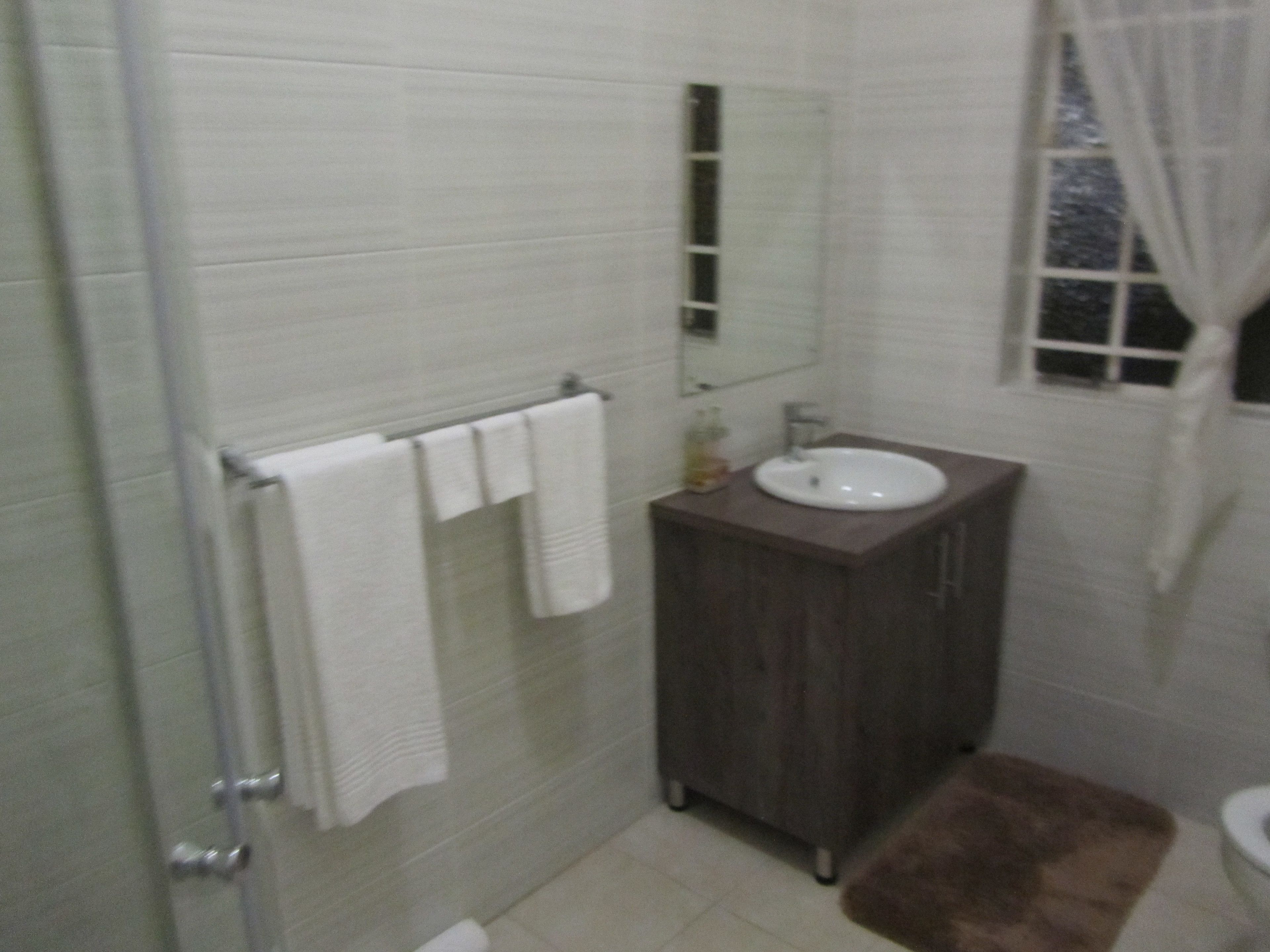 A bathroom with a white sink, a mirror, and a towel rack.