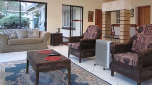A spacious living area with a sofa, two armchairs, a coffee table, and a fireplace.