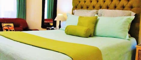 Ein Bett mit einer gesteppten Kopfteil, mehreren Kissen und einer grünen Tagesdecke.