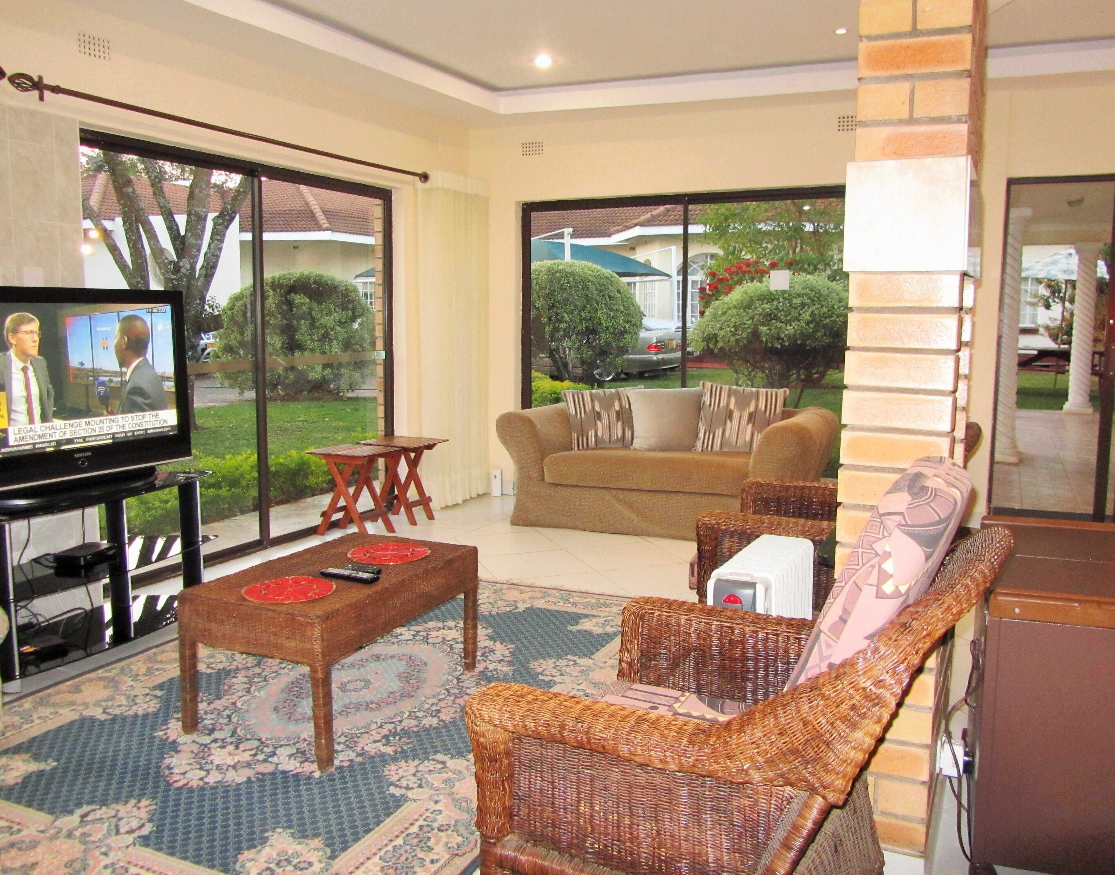 A living room with a television, a sofa, a coffee table, and wicker chairs.