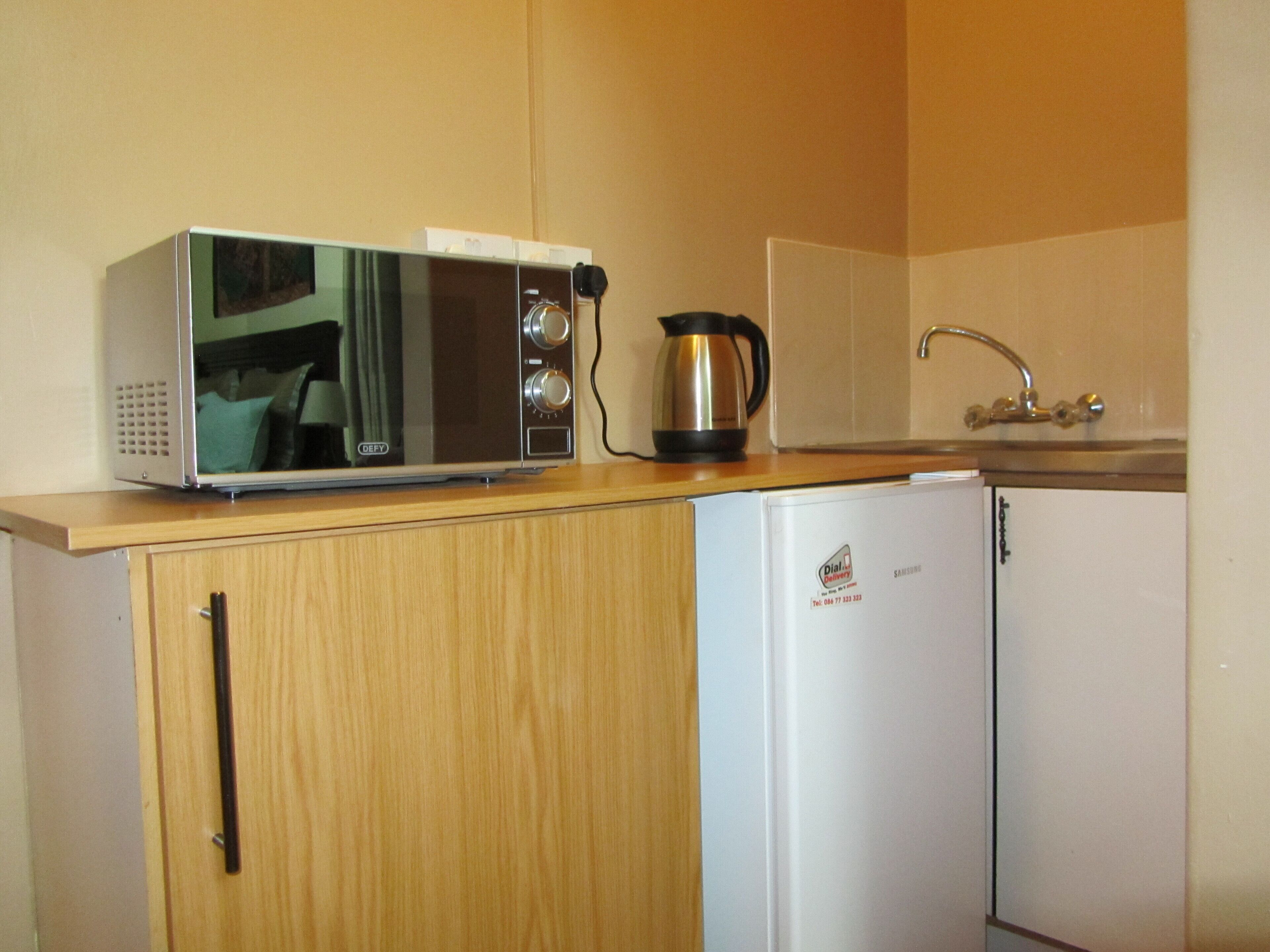 A kitchenette with a microwave, a coffee maker, and a refrigerator.