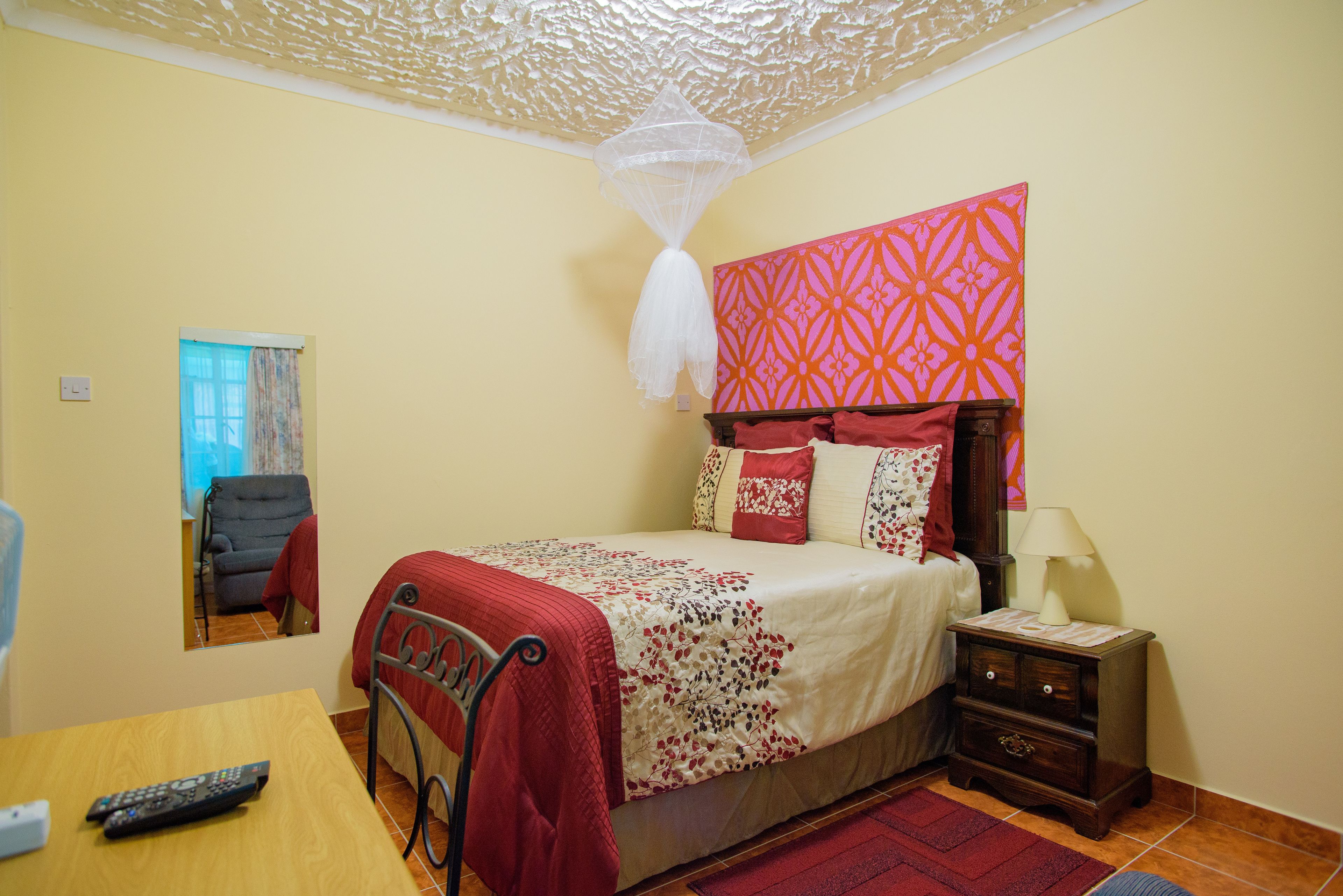 A bedroom with a bed, bedside table, and a mirror.