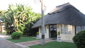 A thatched-roof building with a paved entrance and a well-maintained lawn.